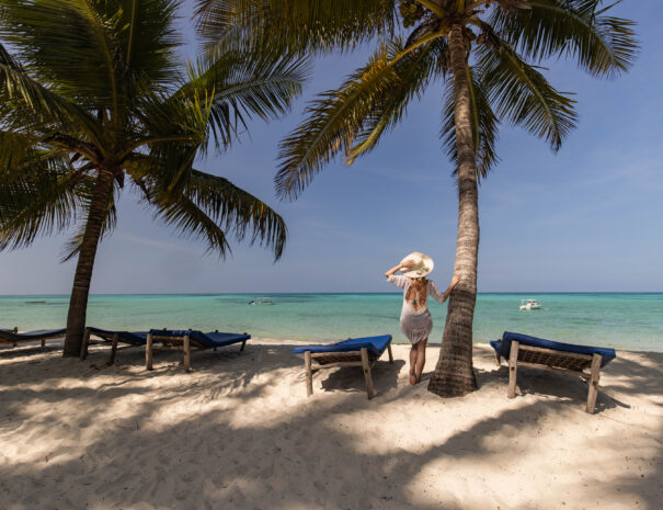 Rear view of carefree woman with sun hat looking at view from a beach. Copy space.
