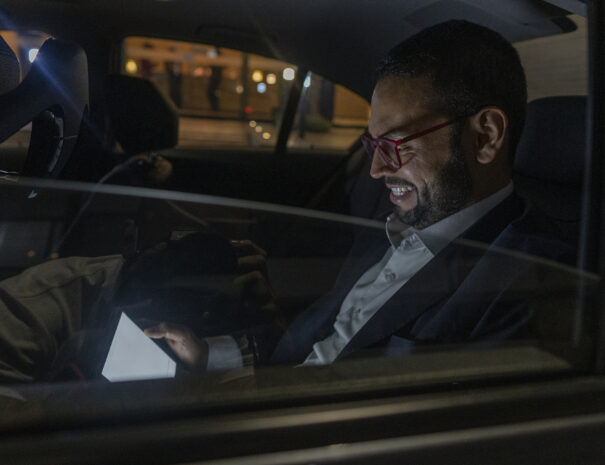 Latino Uber passenger from Bogotá Colombia between 30 and 39 years old, checks his tablet while smiling and wearing his suit