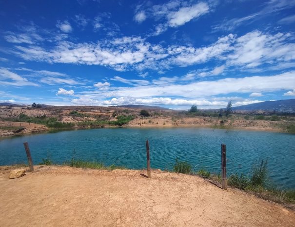 A serene and mesmerizing view of the Pozos Azules in Villa de Leyva, where the crystal-clear, vibrant blue waters contrast beautifully with the surrounding dry, rocky terrain. The pools, nestled in a vast landscape, exude a sense of tranquility and mystery, offering a unique natural spectacle in the heart of Colombia's Boyacá region.