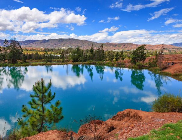 Villa de Leyva, Colombia - One of the pools of water near the Andes town of Villa de Leyva, known locally as Pozos Azules, or translated into English, Blue Pools. The area is semi arid and like a desert in certain places. Even though the elevation today is over 7000 feet above mean sea level, millions of years ago all of this area was under the sea: it is therefore not difficult to imagine why the land today is a semi desert. The plastic tented areas in the background are where vegetables are being grown. The plastic sheets shield the vegetables from unnecessary climatic conditions. A few local tourists are seen in the image but they are far enough not to be recognised. Photo shot in the morning sunlight; horizontal format. Camera: Canon EOS 5D MII. Lens: Canon EF 24-70mm F2.8L USM.